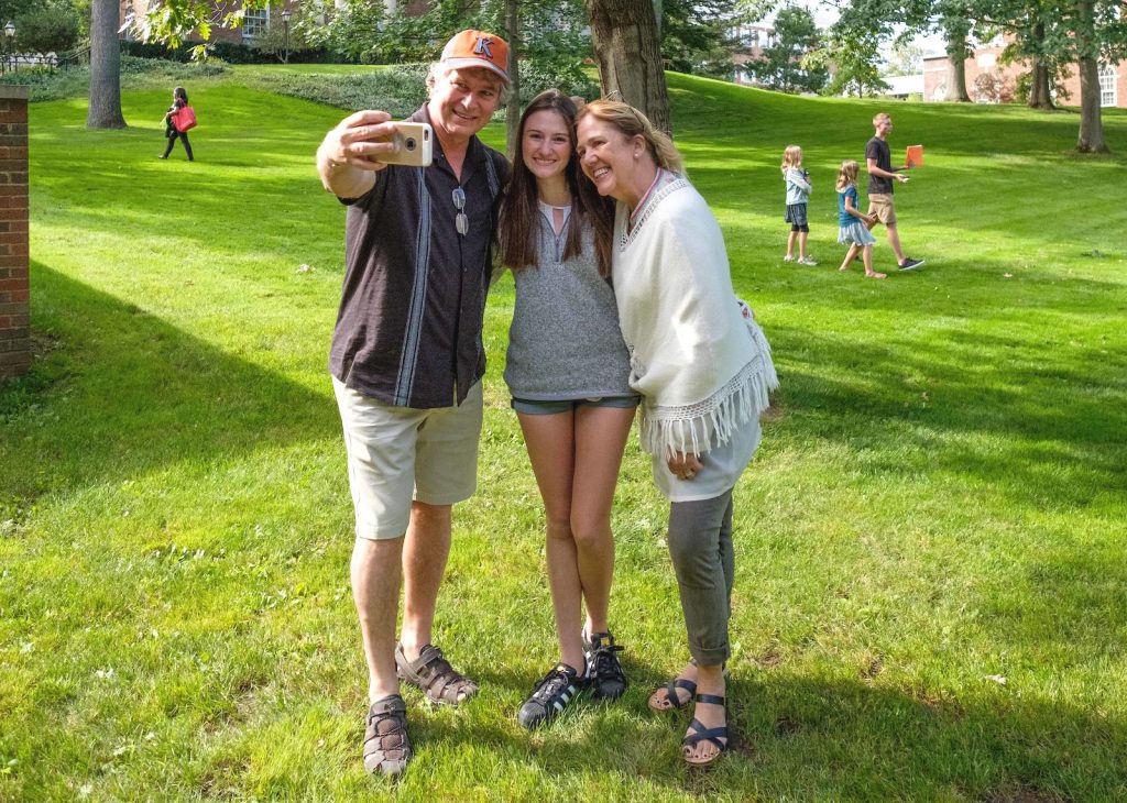 K parents taking a picture with their student on the quad.